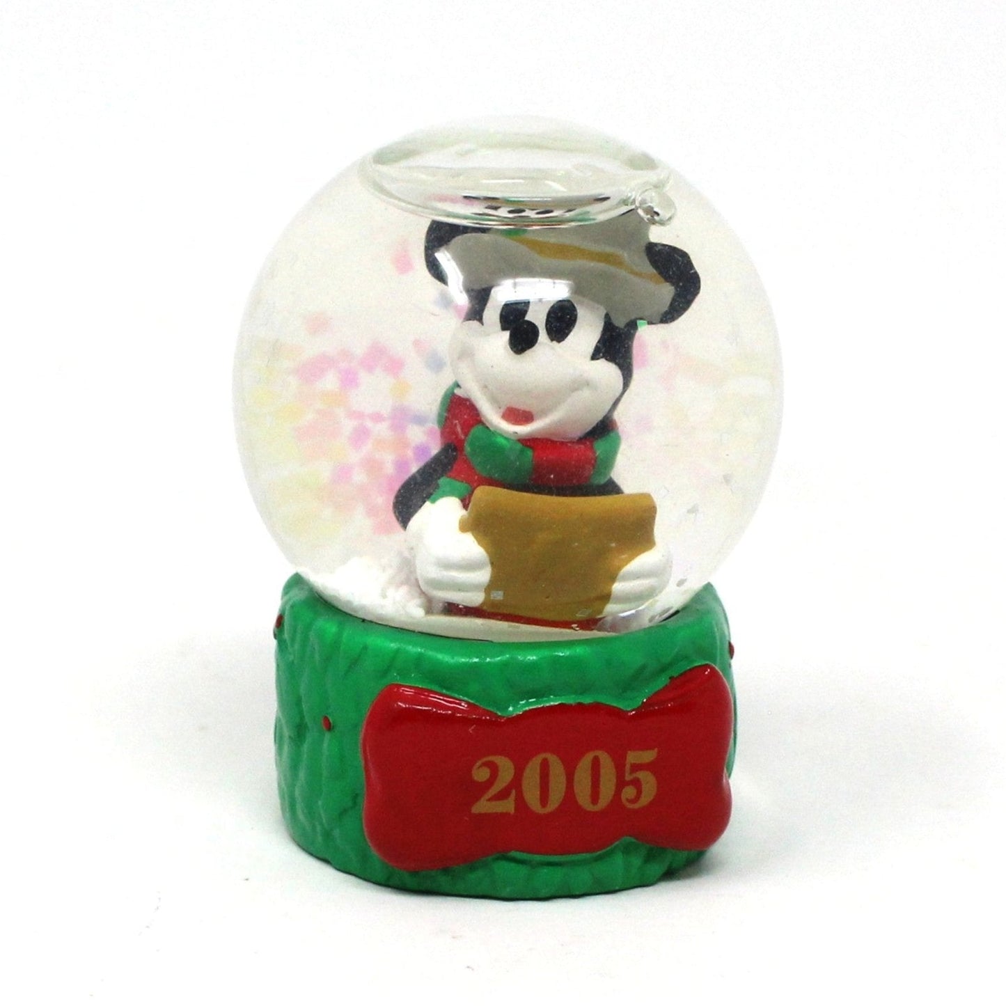 A mini Christmas snow globe featuring Mickey Mouse caroling, with a red and green scarf, hat, and holding a songbook. The base is bright Christmas green and it's dated 2005.