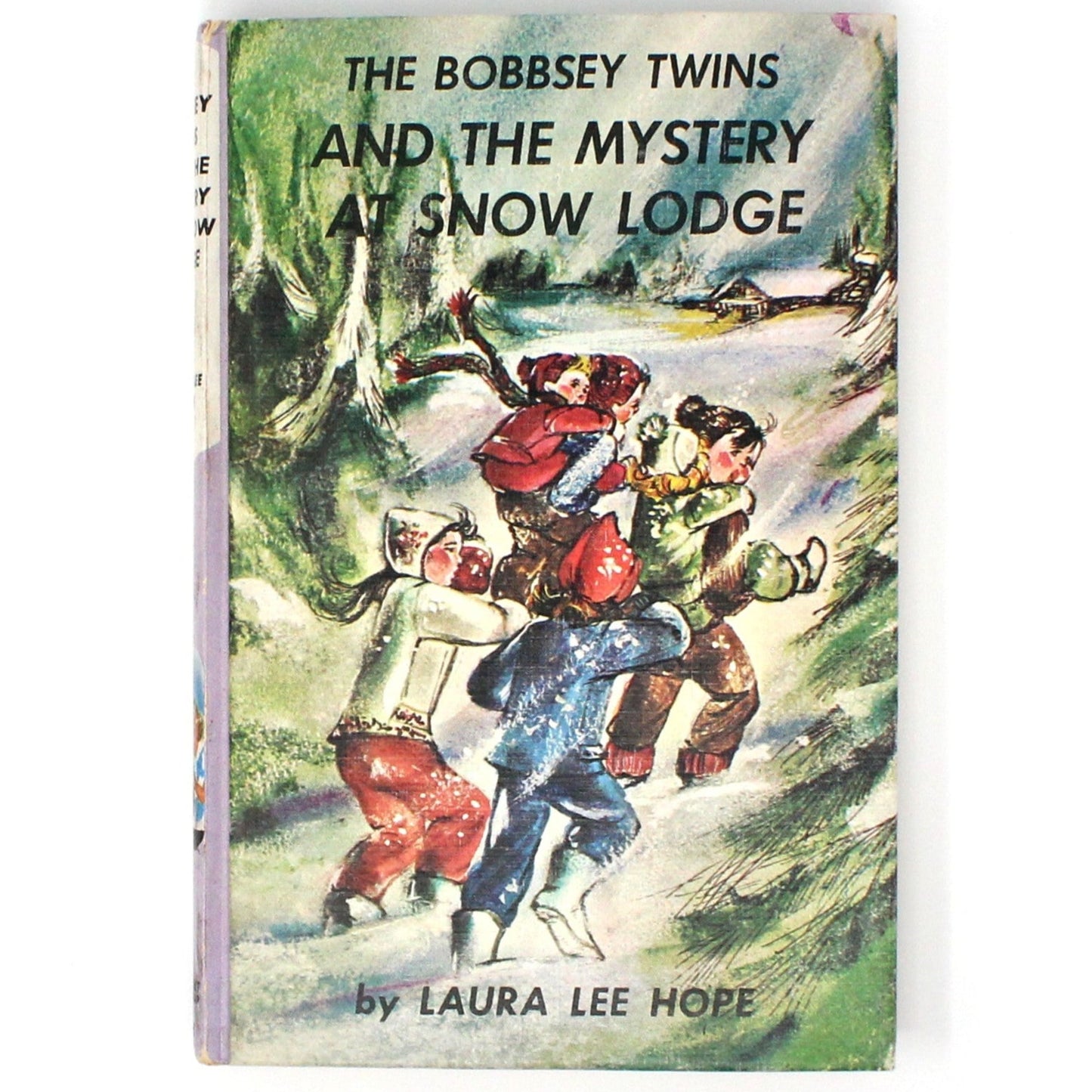 vintage children's book titled 'The Bobbsey Twins And The Mystery At Snow Lodge' showing illustrations of the Bobbsey twins and other characters in a snowy setting.