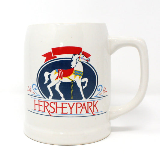 A ceramic beer mug with a colorful illustration of a carousel horse and the text 'Hershey Park' on it. Vintage collectible
