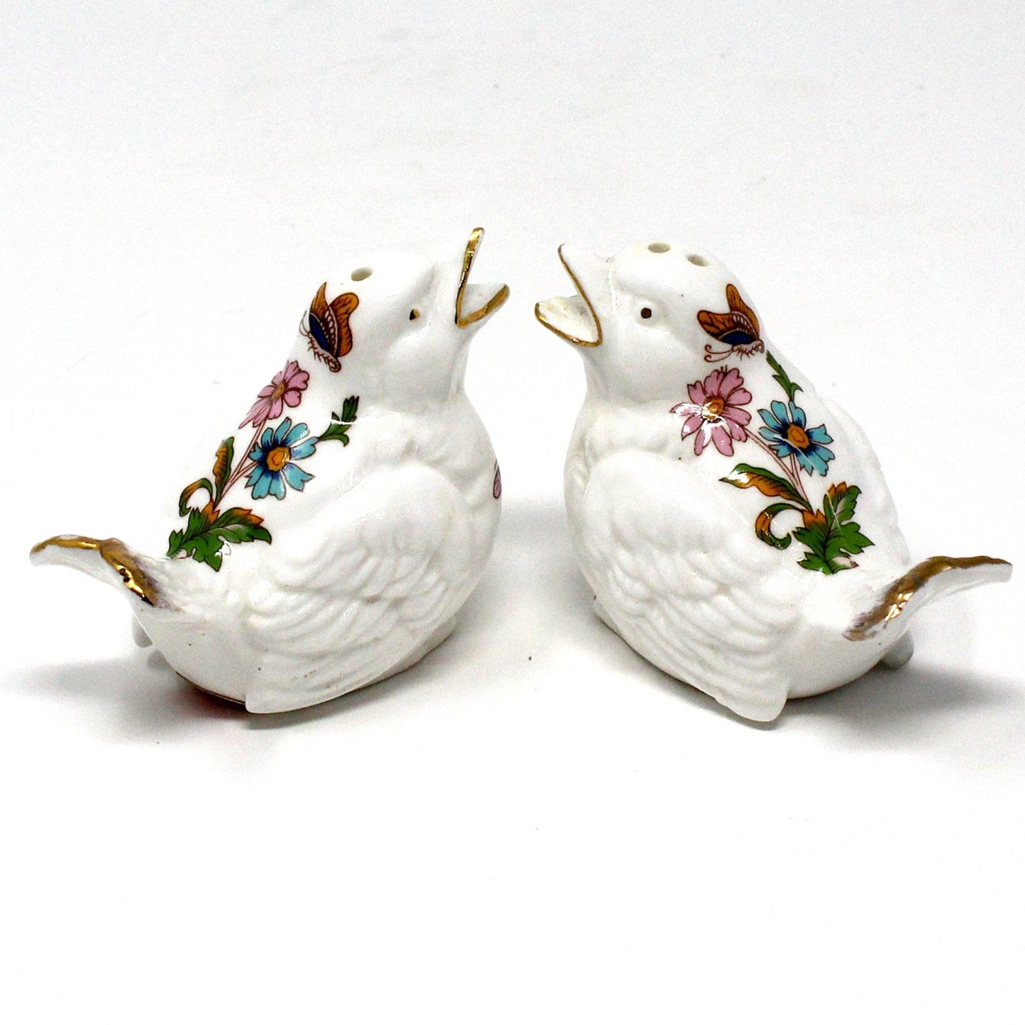 Two vintage salt and pepper shakers, white ceramic birds with floral & butterfly designs and gold accents