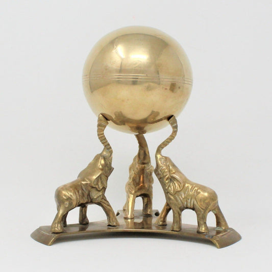 Vintage brass elephant sculpture featuring three elephants holding up a round brass sphere.