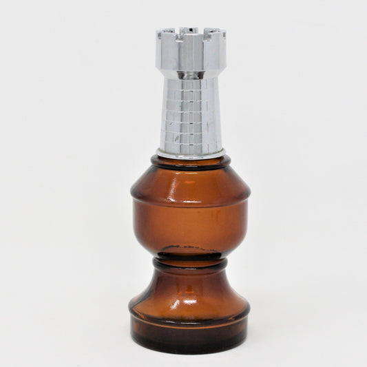 A vintage Avon after-shave decanter in the shape of a brown glass chess rook piece with a silver top.