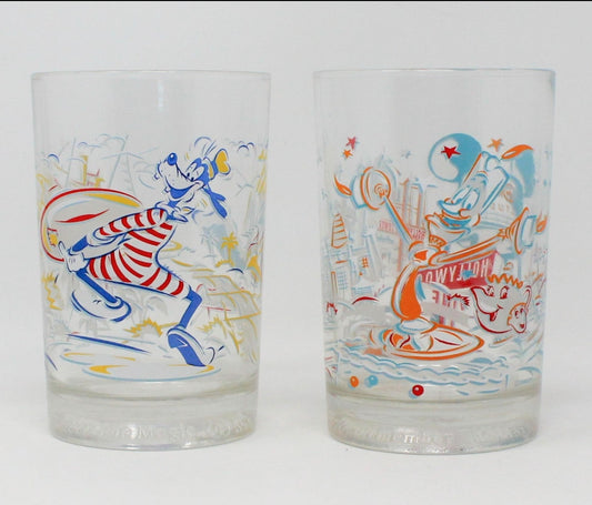 A pair of vintage Disney World 25th anniversary glasses, one with an illustration of Lumiere from Beauty and the Beast and the other featuring Goofy at Typhoon Lagoon and Blizzard Beach.