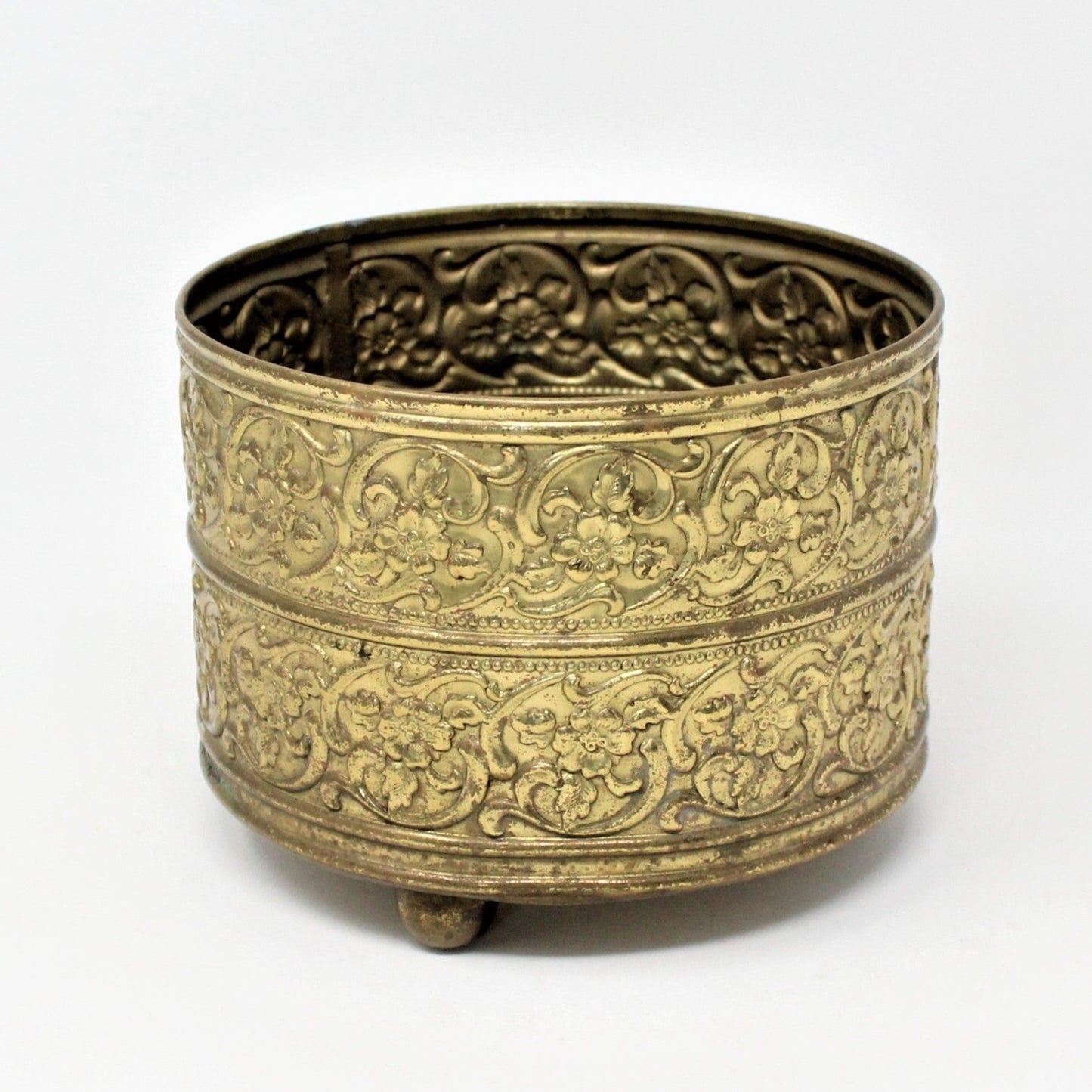 Vintage brass planter or vase with embossed blossoms and three round feet.