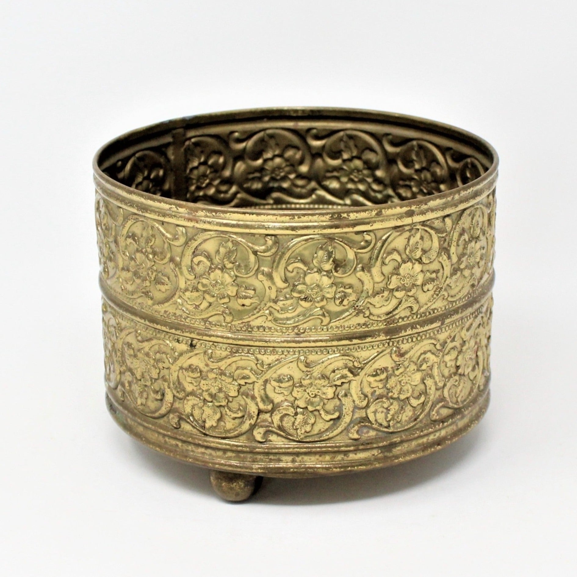 Vintage brass planter or vase with embossed blossoms and three round feet.