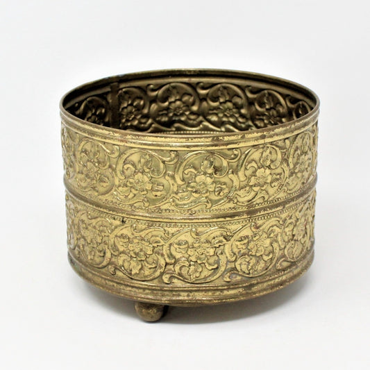 Vintage brass planter or vase with embossed blossoms and three round feet.