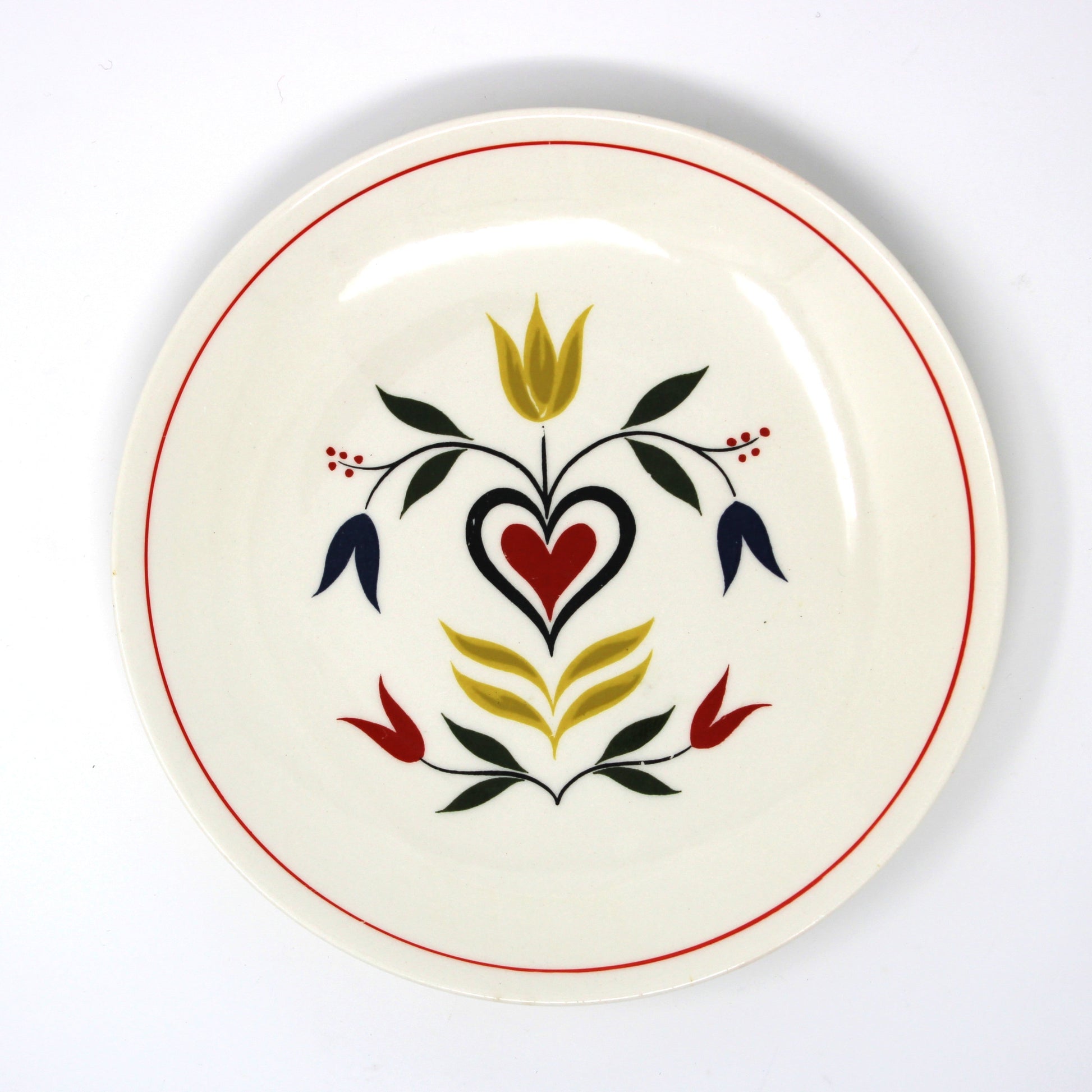 Ceramic plate with decorative heart and floral design on an off-white background