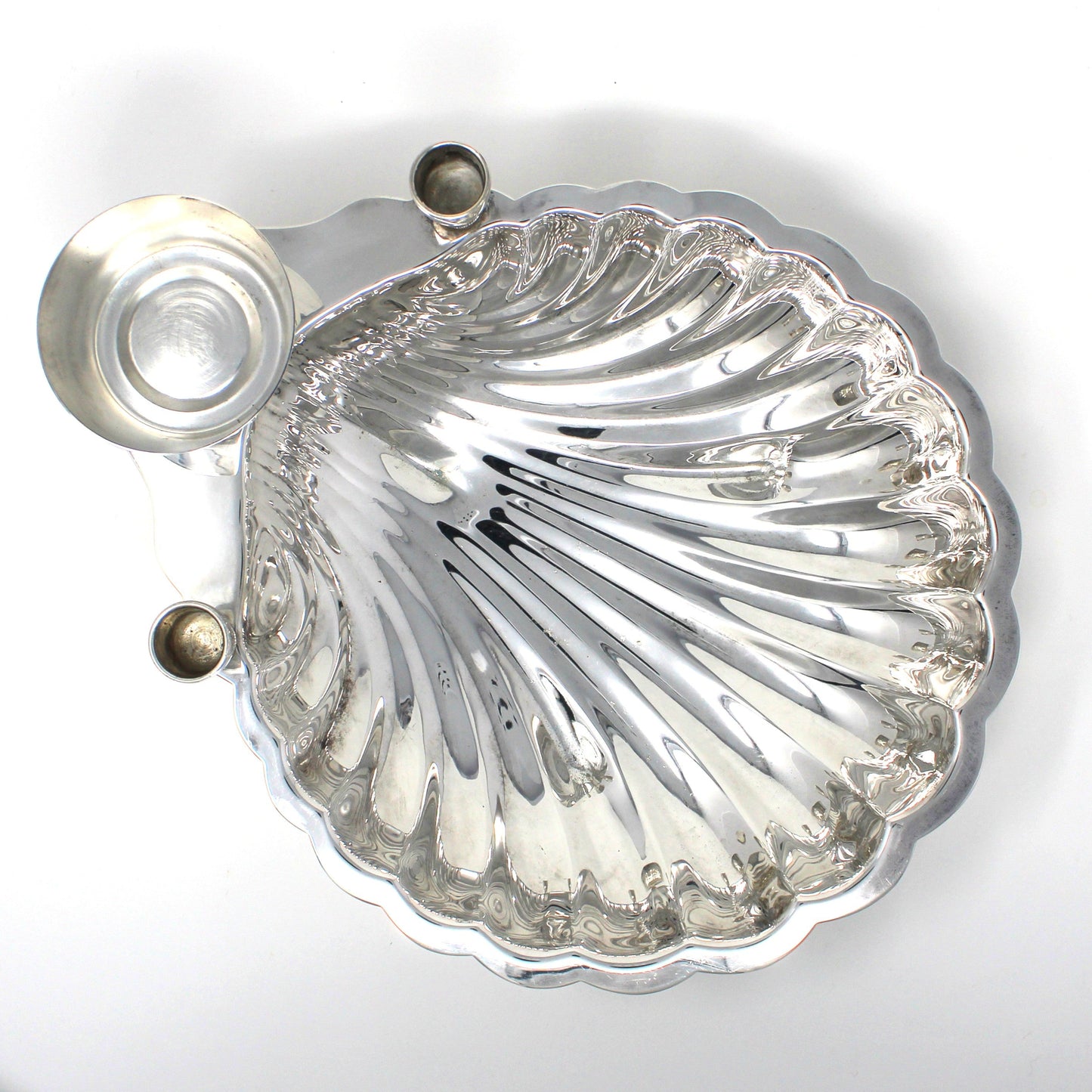 Top view of a silver shell-shaped serving dish with sauce bowl and candle holders.