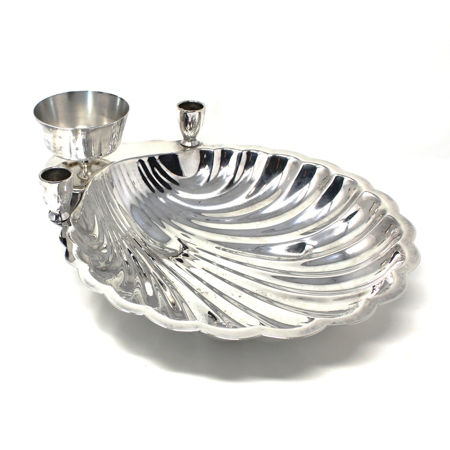 Silver shell-shaped serving dish and cup with two taper candle holders.