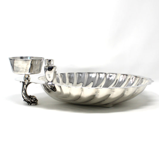 Side view of silver clamshell bowl with cup and dolphin shaped foot.