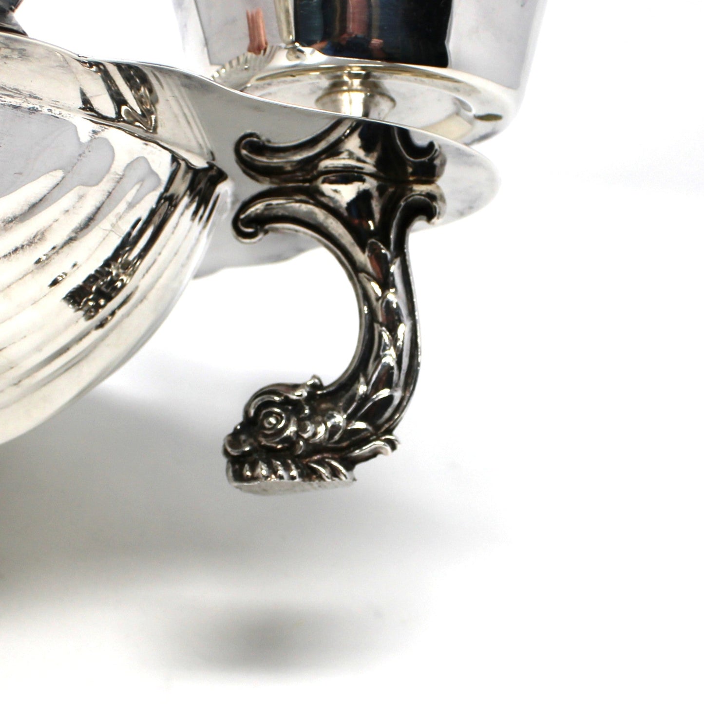 Up-close view of dolphin shaped foot on silverplated clamshell bowl