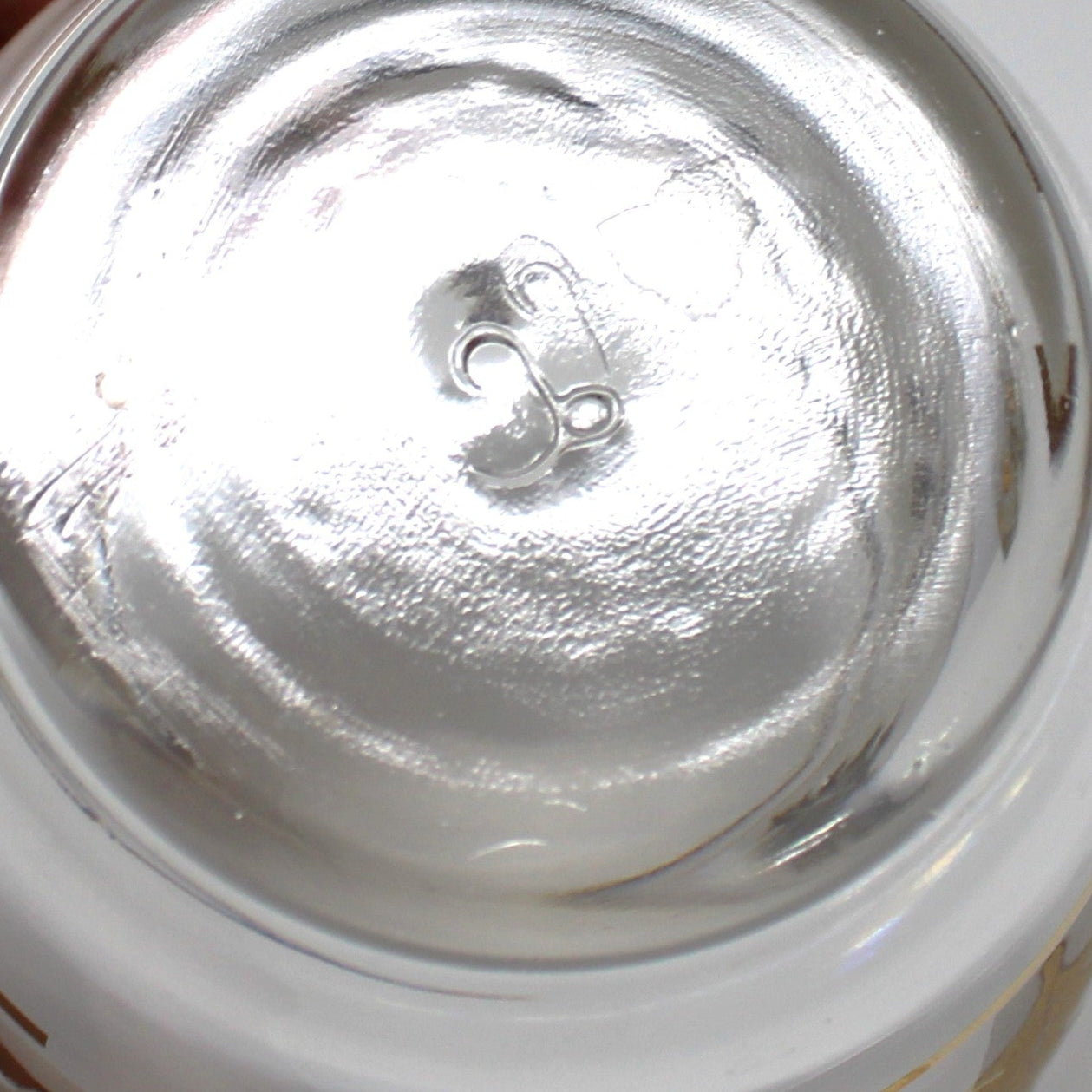 Hand holding a jar with a white lid on a white surface