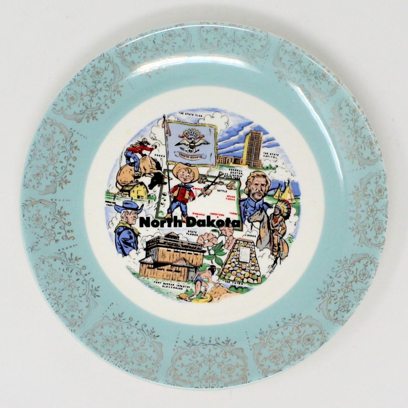 A vintage ceramic decorative state plate. North Dakota state map design, with illustrations of landmarks, cowboys, and a flag.