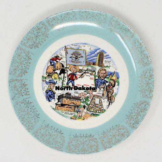 A vintage ceramic decorative state plate. North Dakota state map design, with illustrations of landmarks, cowboys, and a flag.