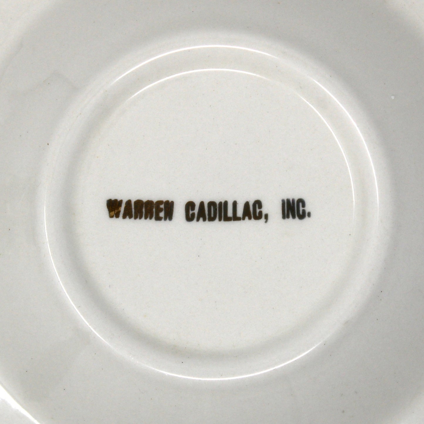 White ceramic plate with 'Warren Cadillac, Inc.' text on a white background