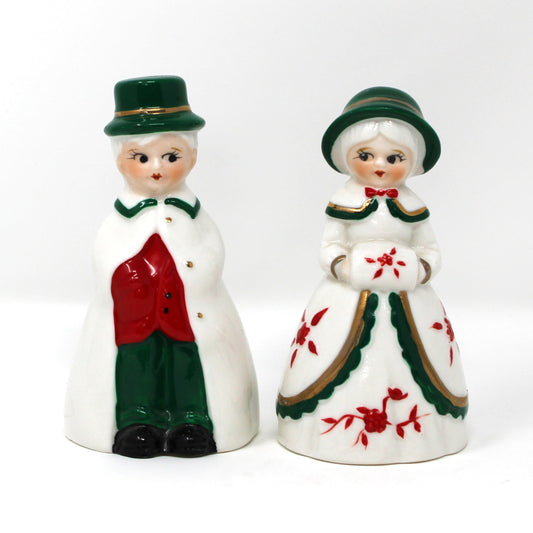 Two vintage porcelain bell-shaped figurines with Christmas attire.
