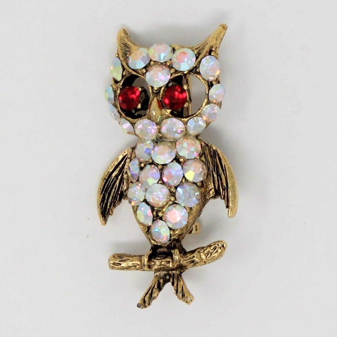 A vintage gold-tone owl brooch with Aurora Borealis and Ruby Red Rhinestones, wings spread wide.