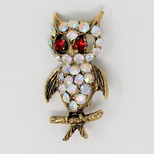 A vintage gold-tone owl brooch with Aurora Borealis and Ruby Red Rhinestones, wings spread wide.