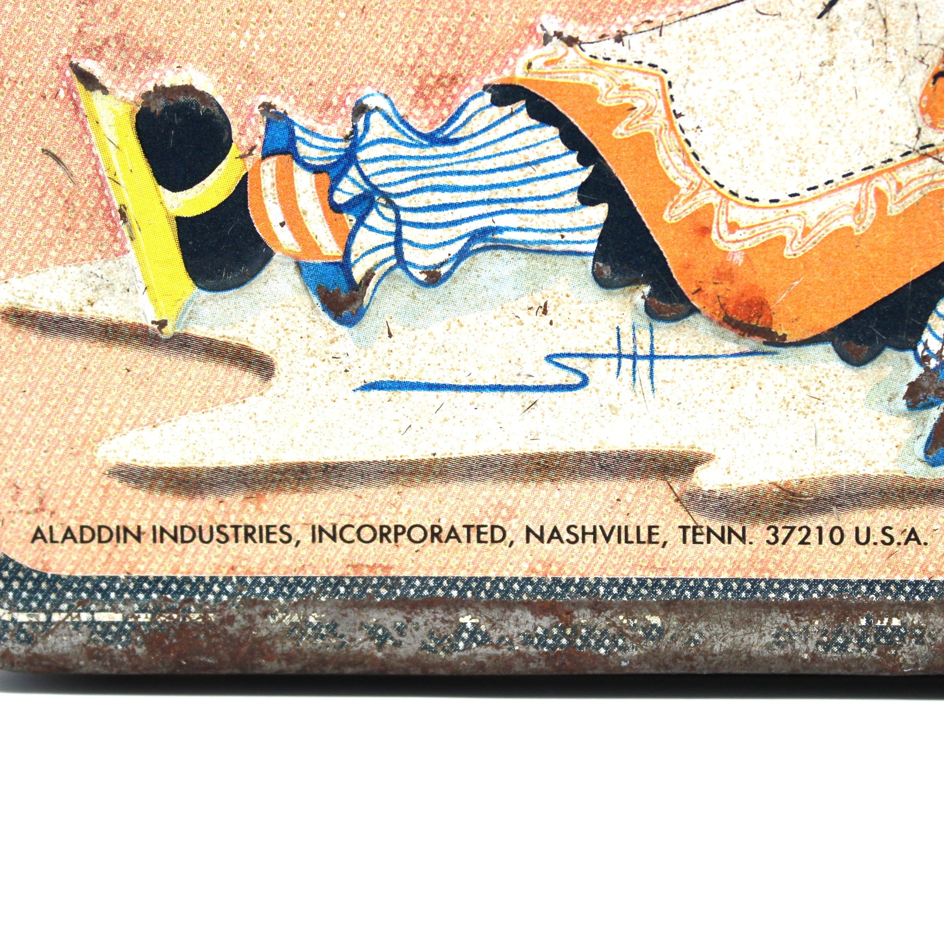 Close-up of a vintage lunch box with colorful graphics and 'Aladdin Industries' branding.