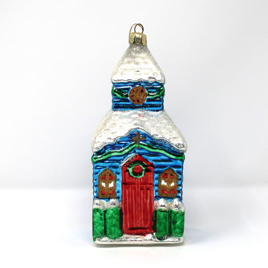 Vintage blown glass ornament of a church with a red door,  snow covered steeple and lots of glitter.