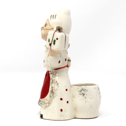 Decorative vintage candle holder shaped like Mrs Claus holding a gift box.