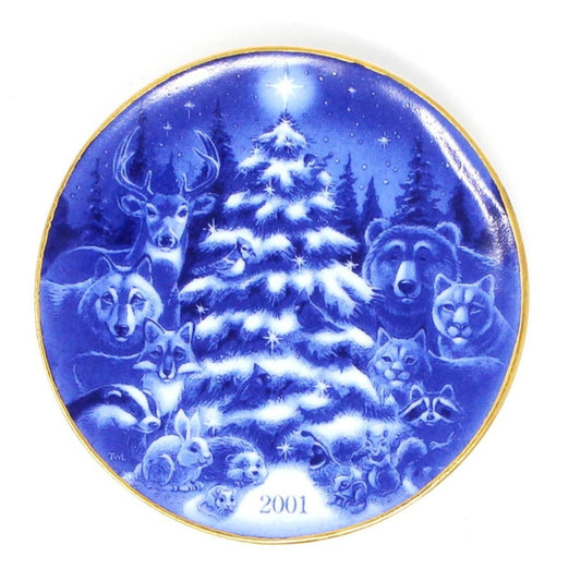 A blue and white porcelain Hallmark Keepsake ornament featuring a Christmas tree with forest animals around it, including a bear, deer, and squirrels. The year 2001 is visible on the ornament.