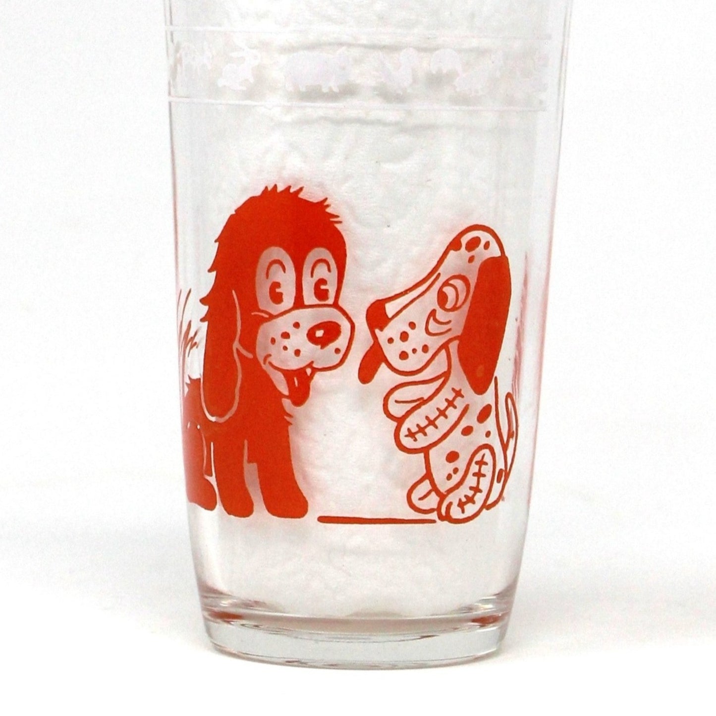 A vintage Hazel Atlas Swanky Swigs tumbler, orange juice glass with a design of a dog and a chicken in orange enamel.