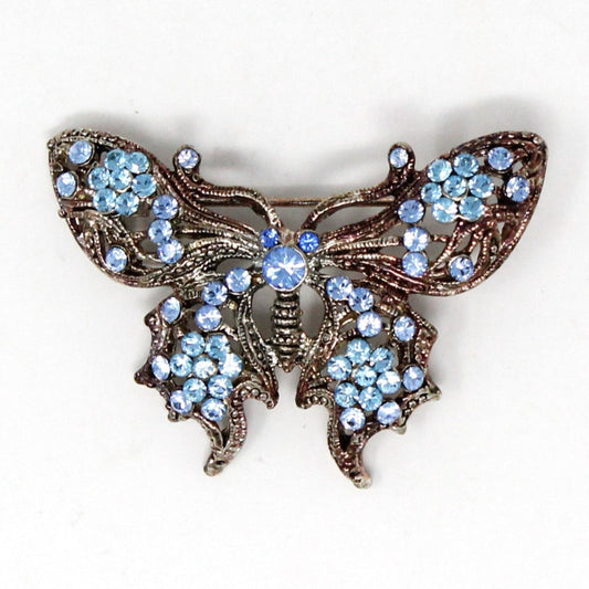 A figural butterfly brooch with blue Swarovski crystals on an antiqued silver tone, with a safety clasp.