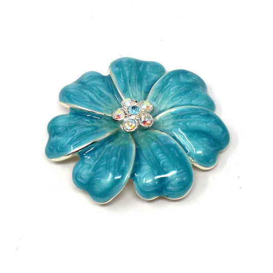 A vintage turquoise blue enamel flower brooch with a rhinestone center and silver-tone metal, displaying signs of wear.