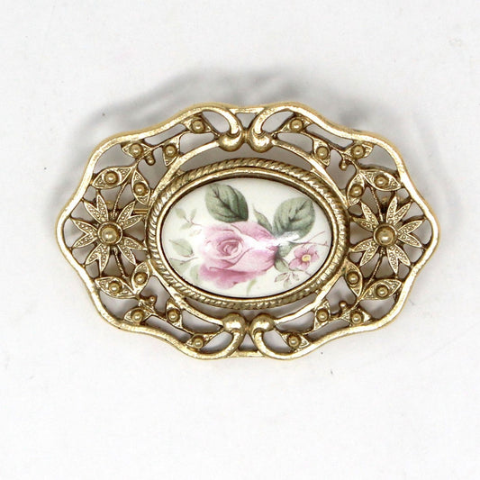 A vintage brooch featuring a pink rose porcelain cameo with gold filigree design. 1928