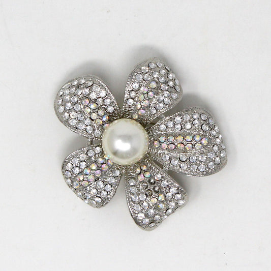 A silver-tone brooch featuring a flower shape with white and AB rhinestone petals and a central faux pearl