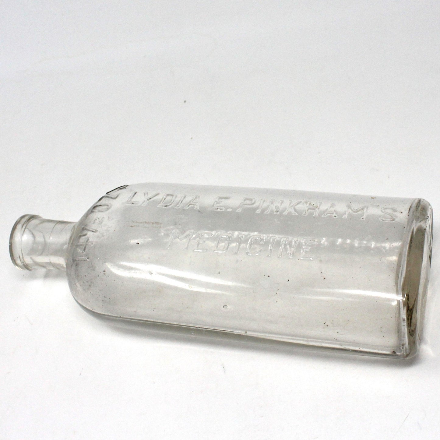 An antique clear glass medicine bottle with embossed lettering, cork closure, and a visible pontil mark, labeled 'Lydia E. Pinkham Medicine'.