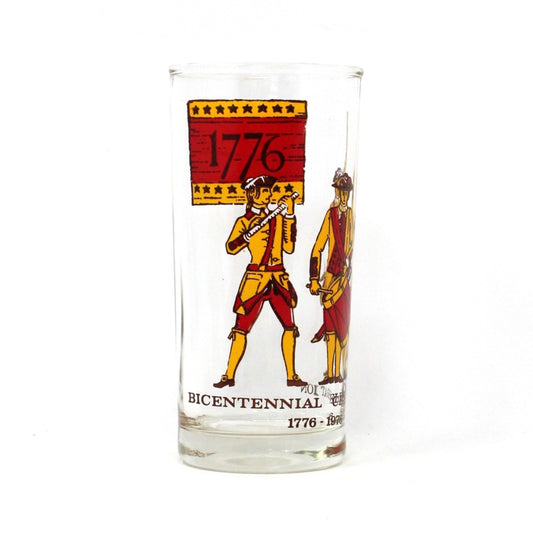A vintage collectible glass with a 'Bicentennial 1776-1976' design, featuring red and yellow enamel illustrations of minutemen.