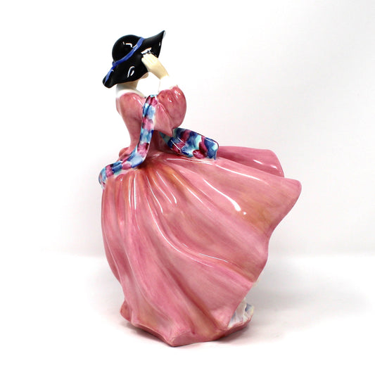 Right side view of vintage porcelain Royal Doulton figurine titled "Top O' The Hill". HN1849, of a woman in a flowing pink dress with blue hat.