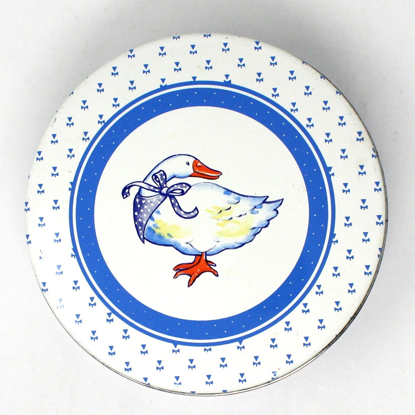 Round ceramic cookie tin, Blue and White with a white goose wearing a blue bandana. The sides have yellow baby geese.