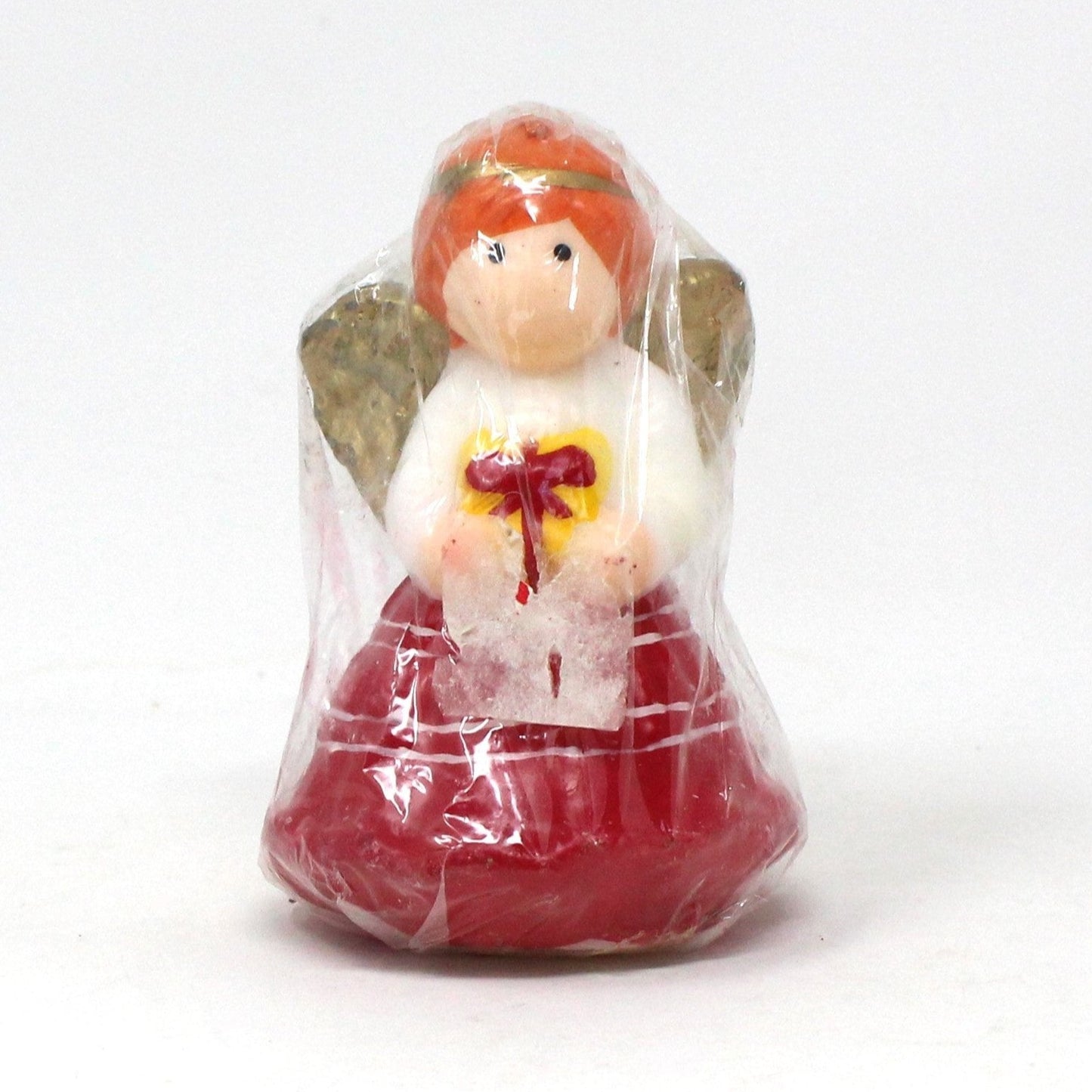 A vintage Christmas angel novelty candle in red and white dress holding a gift, wrapped in original plastic, never burned.