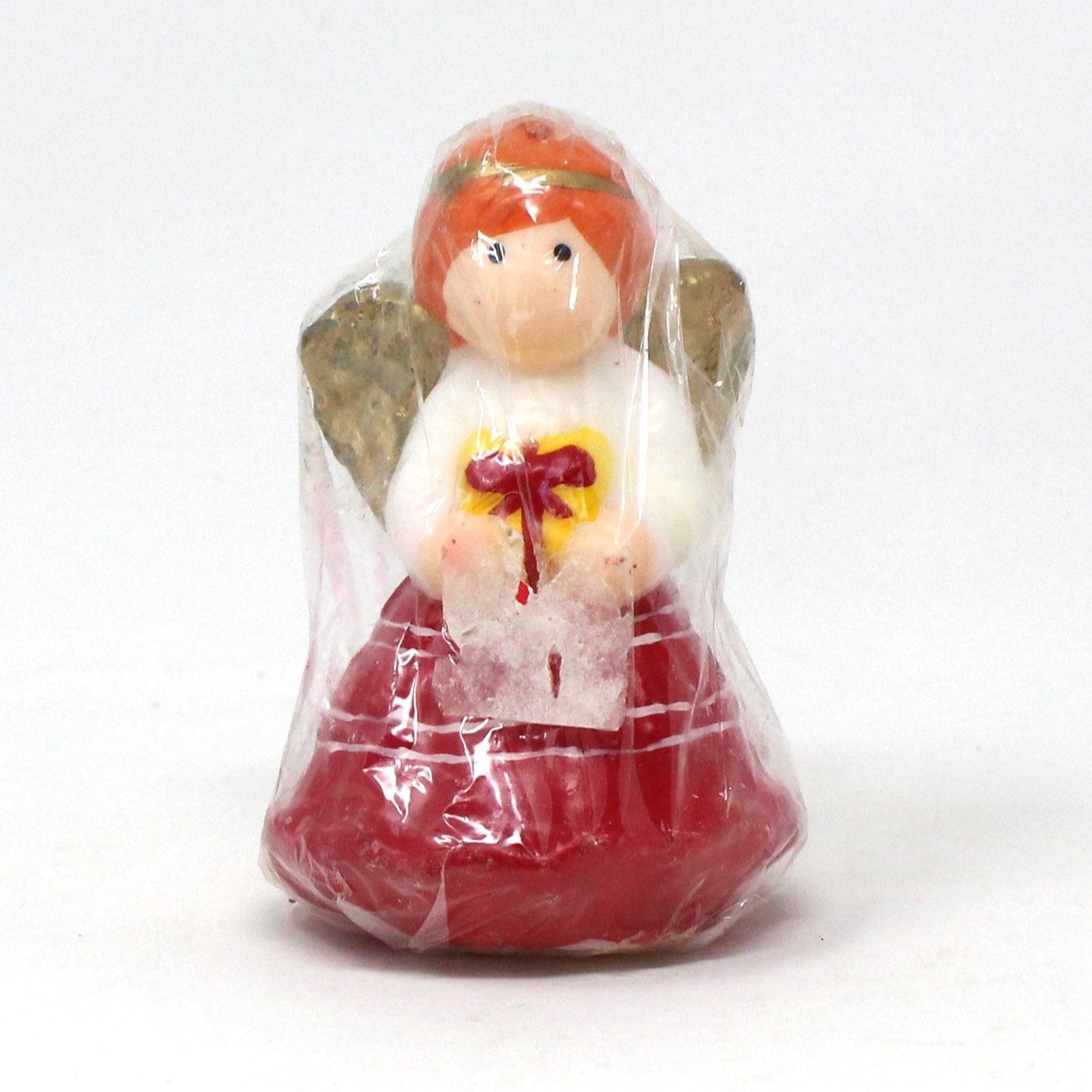 A vintage Christmas angel novelty candle in red and white dress holding a gift, wrapped in original plastic, never burned.