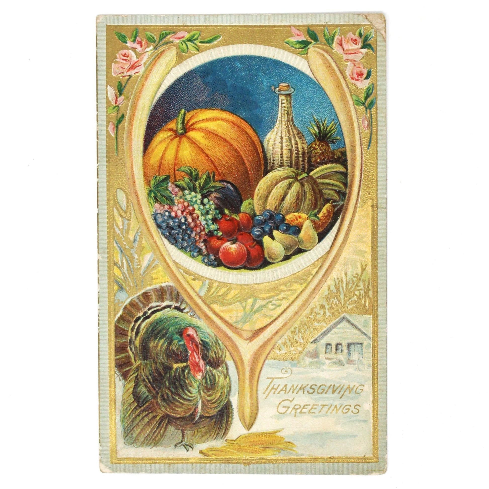 Antique embossed and gilded Thanksgiving postcard featuring an illustration of harvest fruits and vegetables, a wishbone, and a turkey with a snowy cabin scene on the bottom, all in a decorative frame with pink roses at the corners.