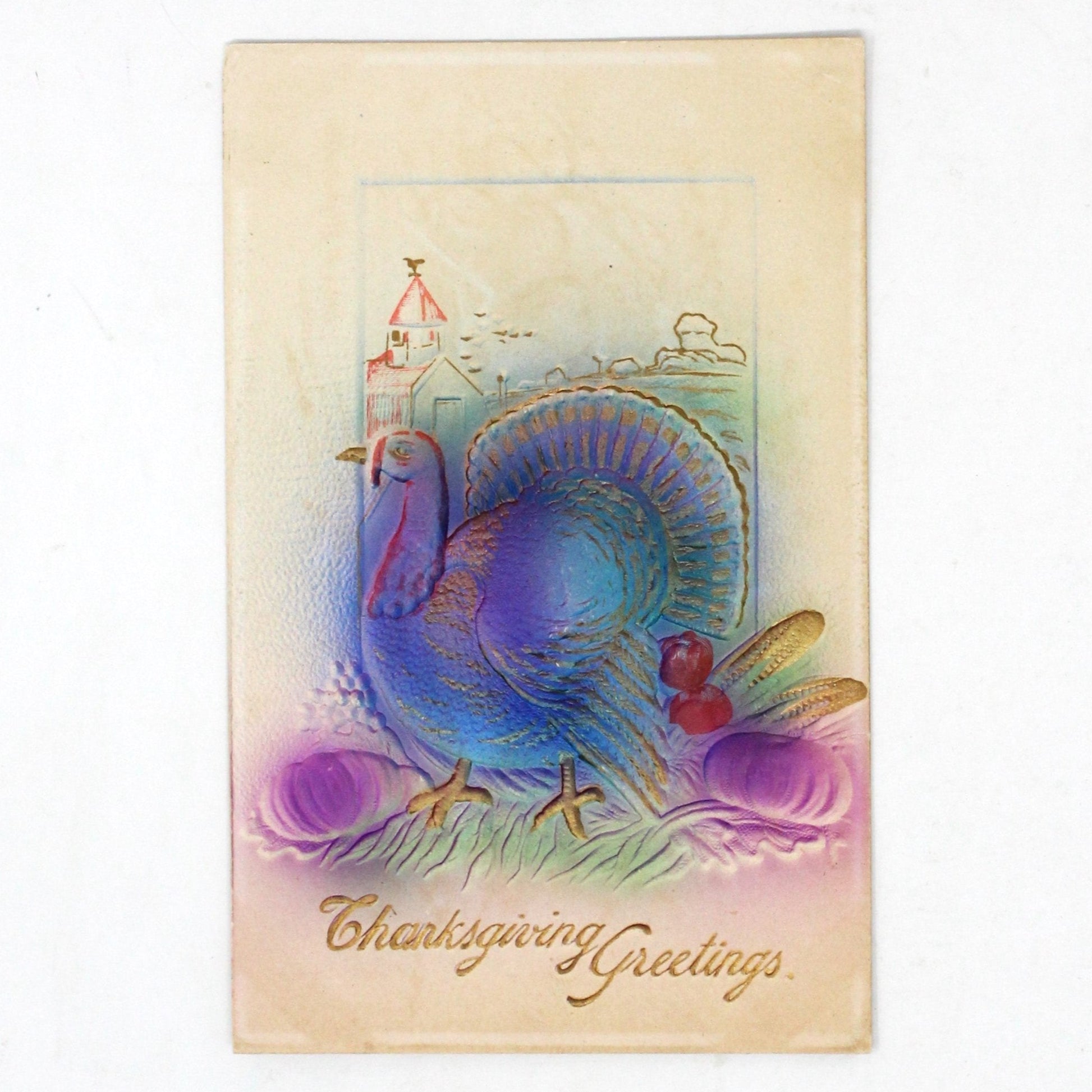 Antique Thanksgiving postcard featuring an embossed and gilded illustration of a turkey with pumpkins and corn, air brushed in lavender and blue, with 'Thanksgiving Greetings' text.