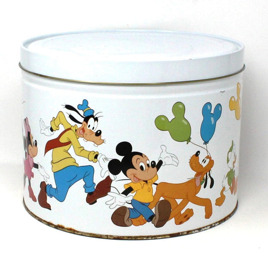 A large metal tin featuring colorful illustrations of Disney characters Mickey, Minnie, Goofy, Donald Duck, and Pluto on a bright white background.