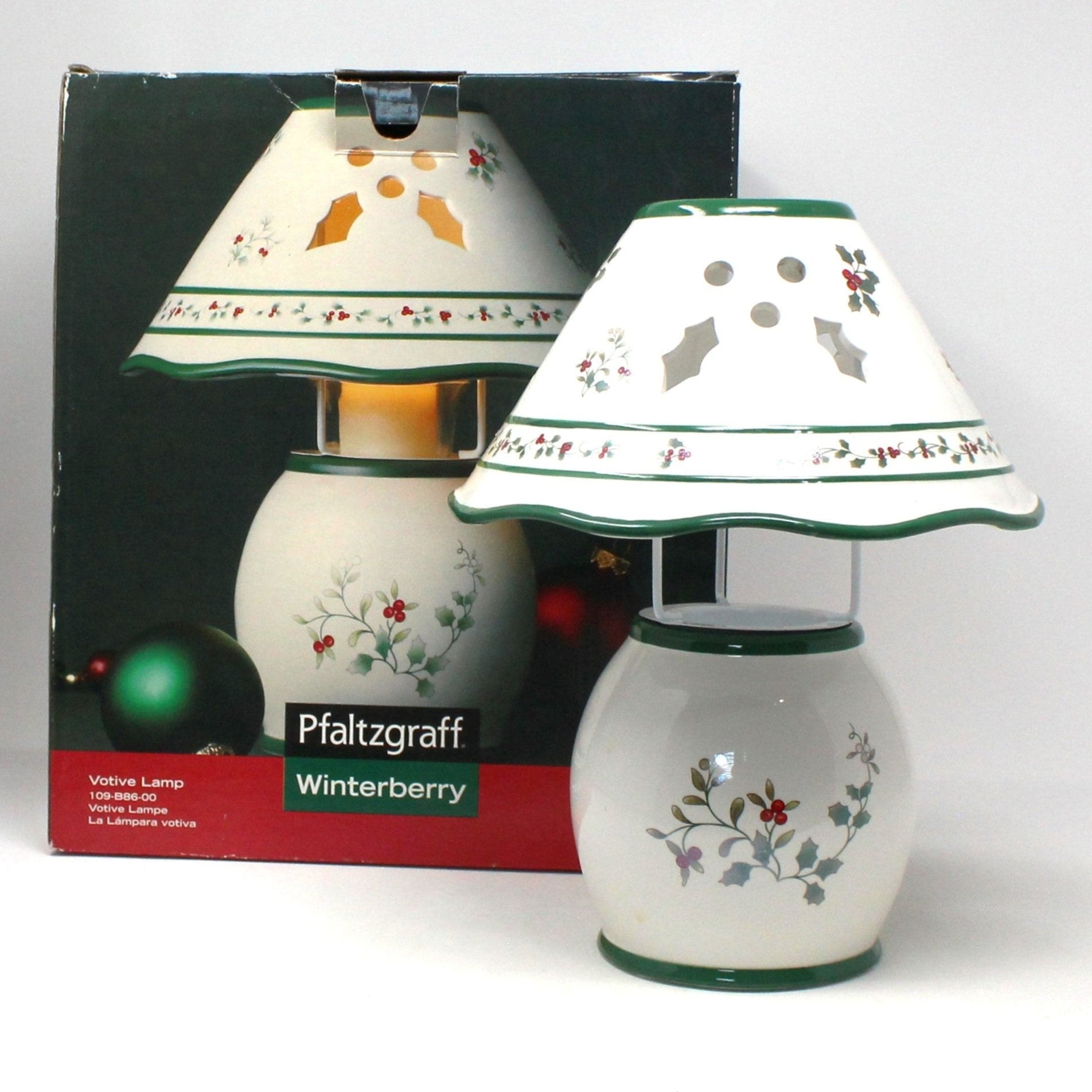 A Pfaltzgraff Winterberry votive candle lamp in a white ceramic shade with green holly leaves and red berries, and holly cut-outs, with its original packaging box.