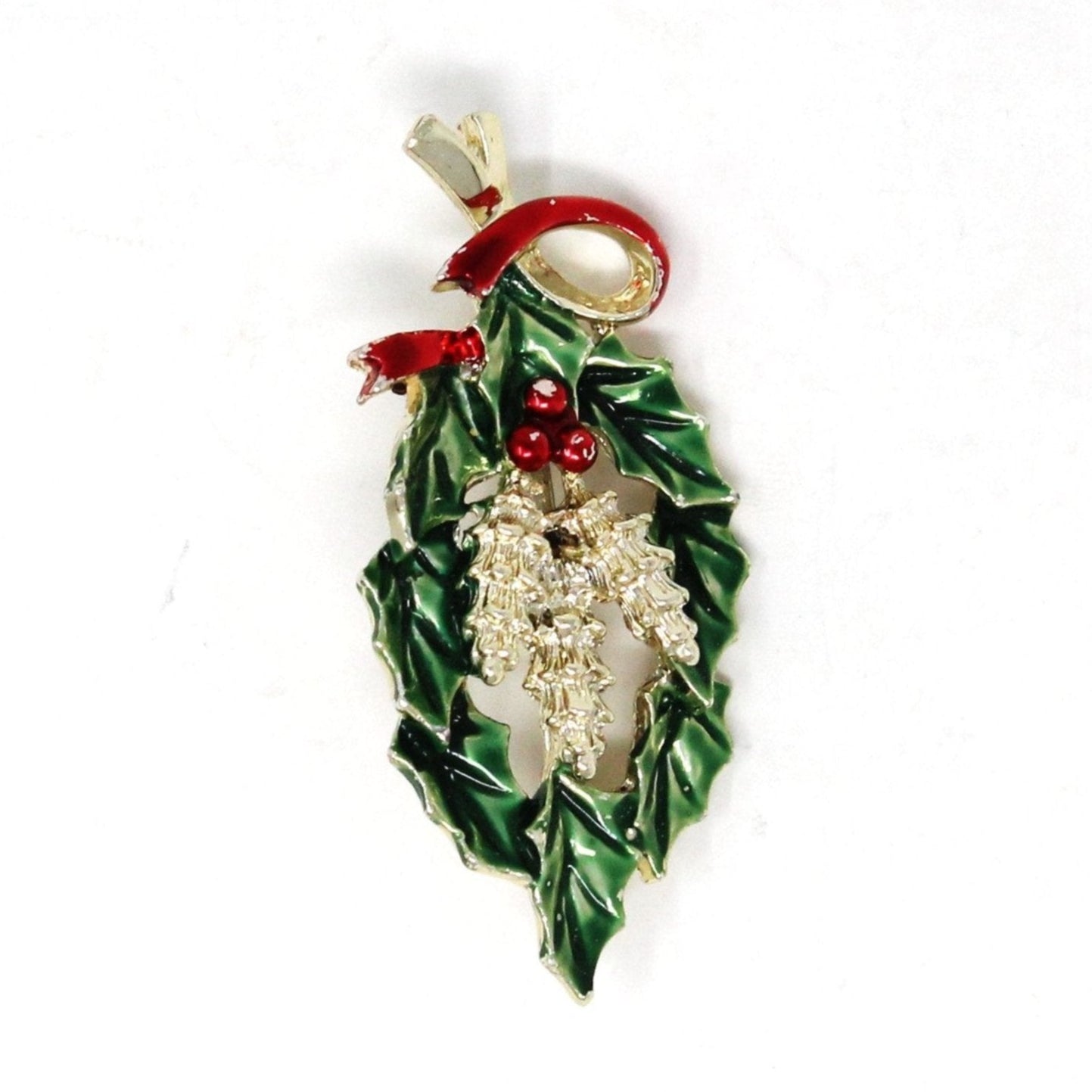 A vintage Gerry's Creations brooch featuring green and red enamel holly branches with pine cones and red berries, attached to a gold-tone metal pin.