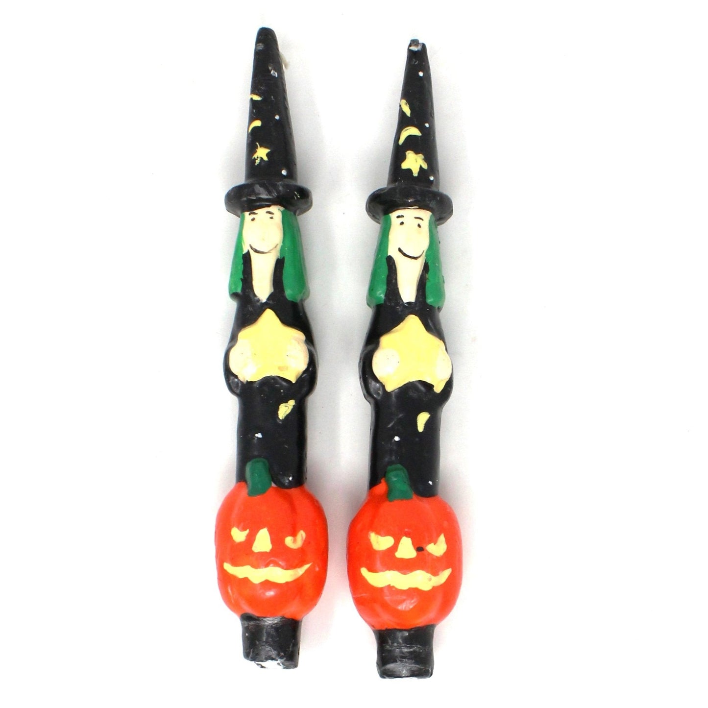 A pair of vintage taper candles featuring a Halloween figural witch & pumpkin design with a black hat adorned with stars and a green hairdo, standing on an orange pumpkin. The candles are unused and have a black base.