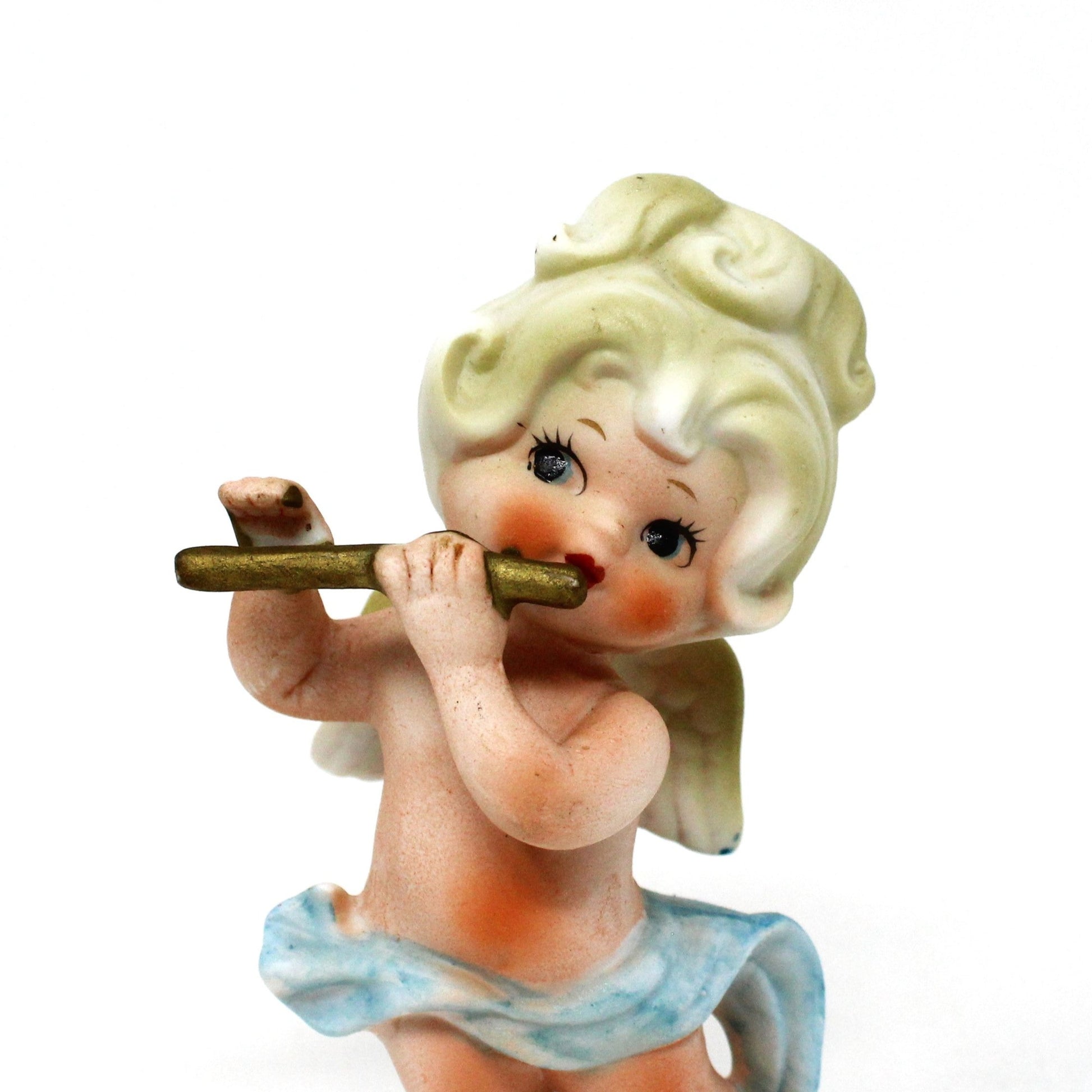 Close up of angel's face on vintage figurine.  Blond angel playing a golden flute.