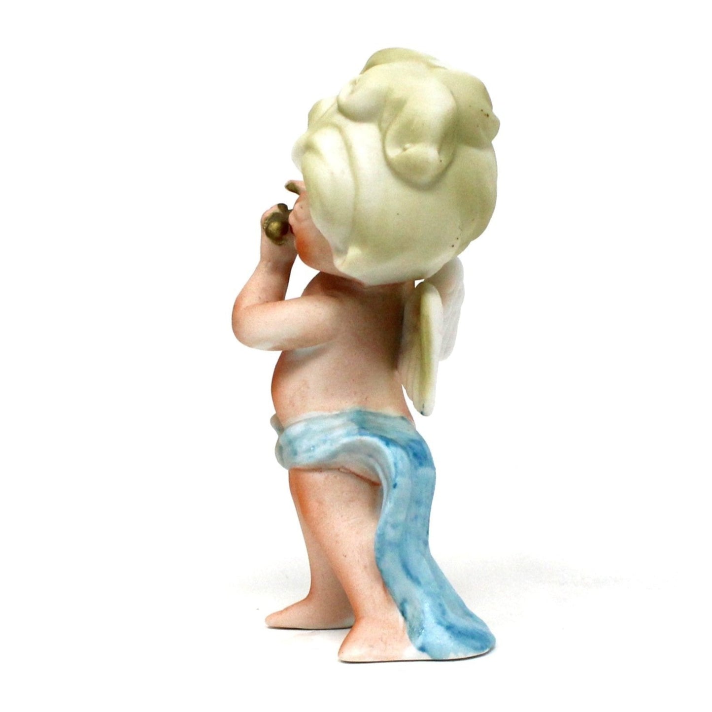 Side view of vintage angel figurine. Blond angel playing flute wearing a blue sash.