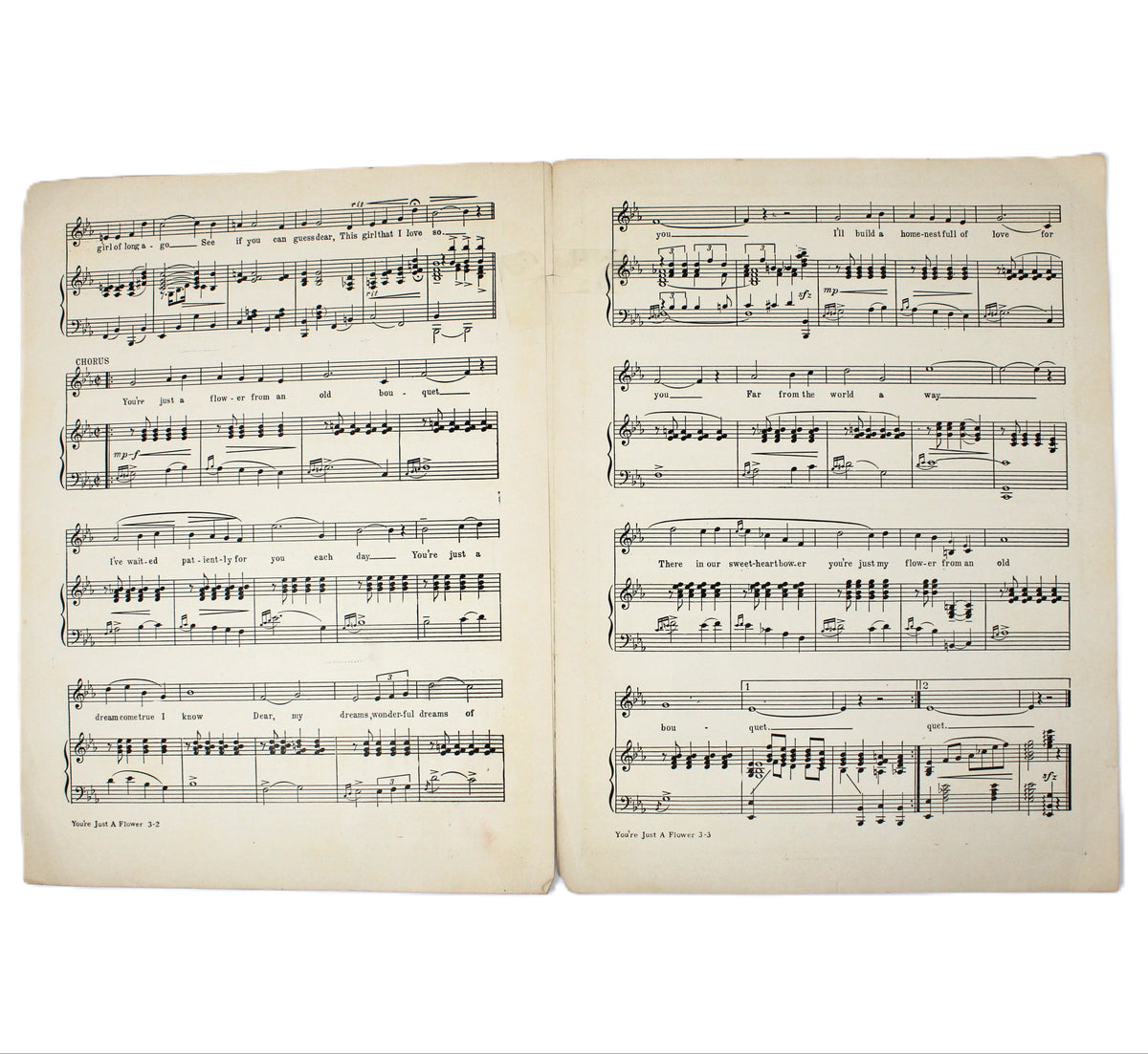 An open vintage sheet music book displaying printed musical notation on aged, yellowed pages against a plain white background.