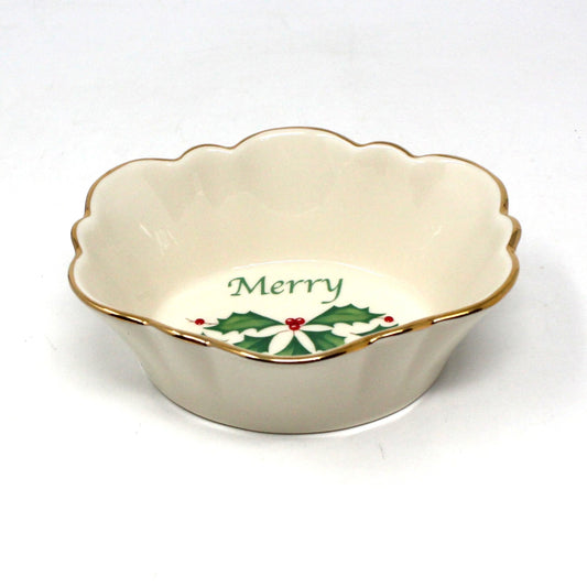 A porcelain Lenox 'Holiday' pattern candy dish with a fluted edge and a central sprig of holly and red berries, with the word 'Merry' on the dish.