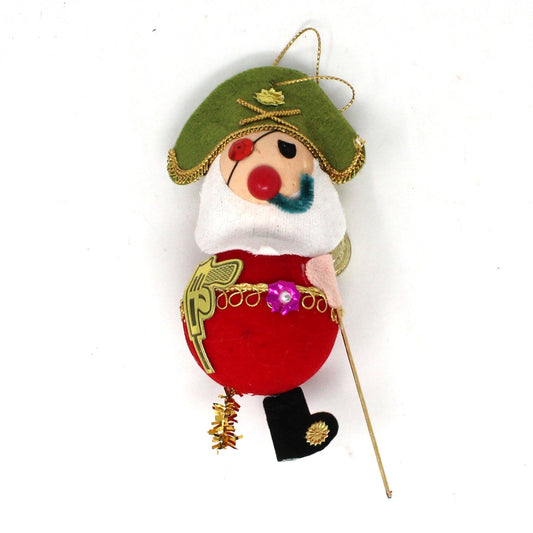 Vintage felt Christmas ornament featuring a one-legged flocked pirate with a pipe and red clothing, including a hat with a gold cord for hanging.