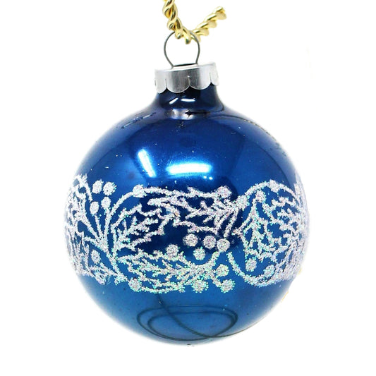 A vintage blue mercury glass Christmas ornament with a white stencil glitter design of holly and berries.