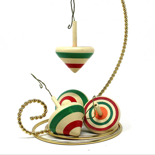 A set of four vintage ornaments, mini wooden spinning tops with red, green, and white stripes.
